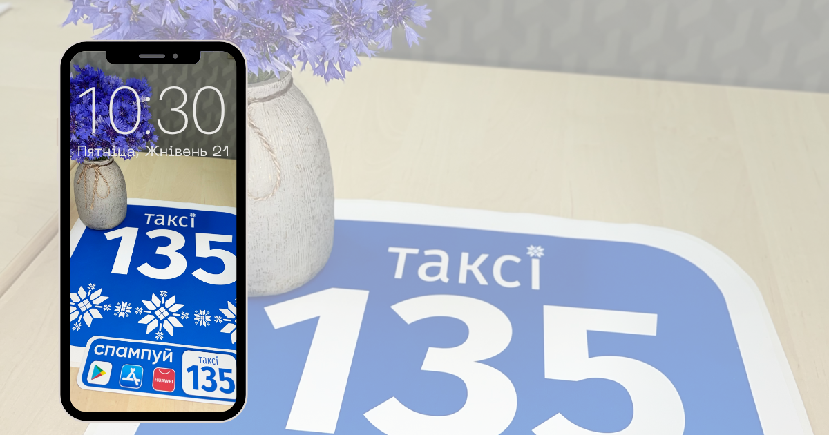 Смартфон i на фоне брэндыраваныя лагатыпы кампаніі Таксі 135